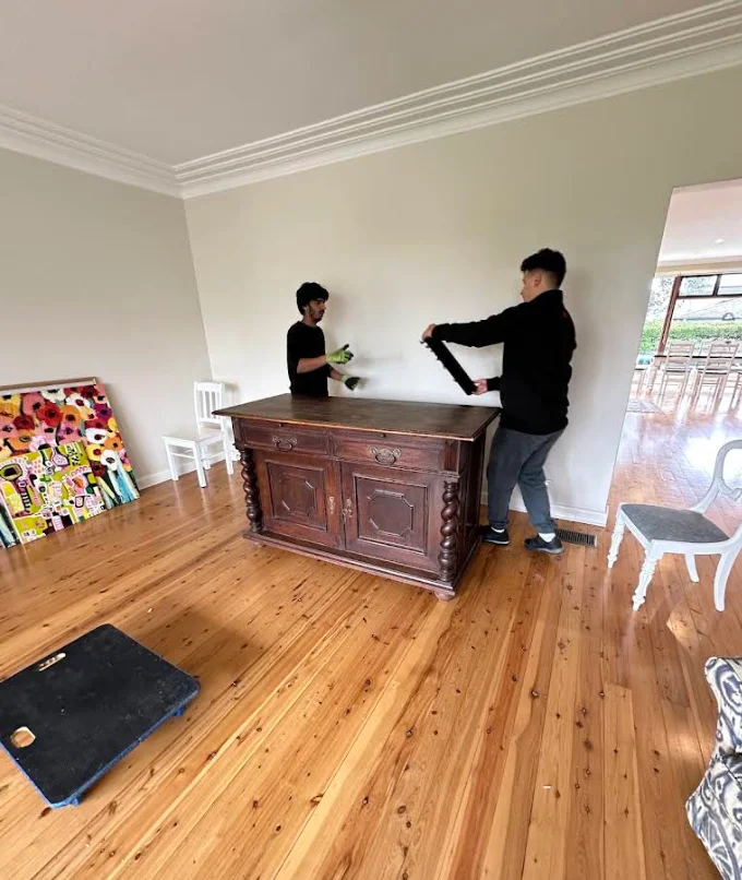 Grey Whales Removals team carefully moving an antique wooden sideboard
